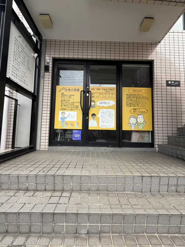 当店の入口。黄色いポスターが貼られたガラス扉で、手前に数段の階段があります
